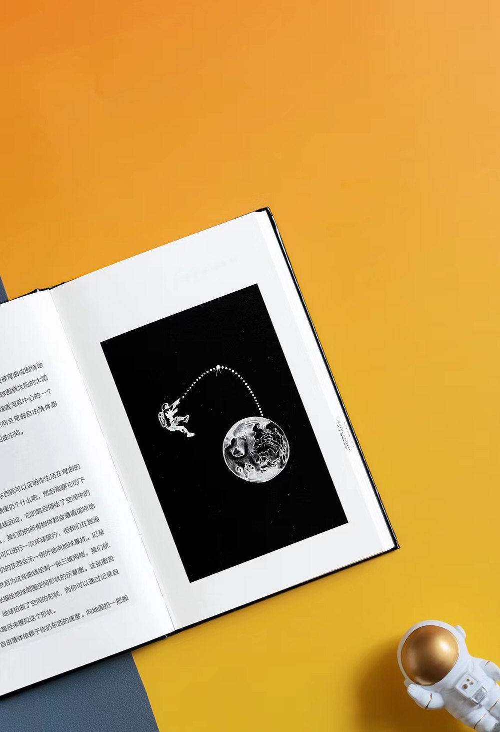 The book open to an interior spread: a black plate showing an astronaut tethered
                  above a planet, facing a page of Chinese text.